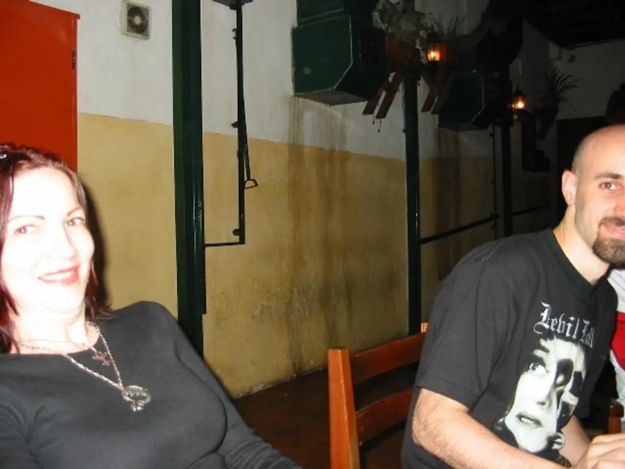 In the image there are two people and behind them there is a wall, there is some equipment attached...