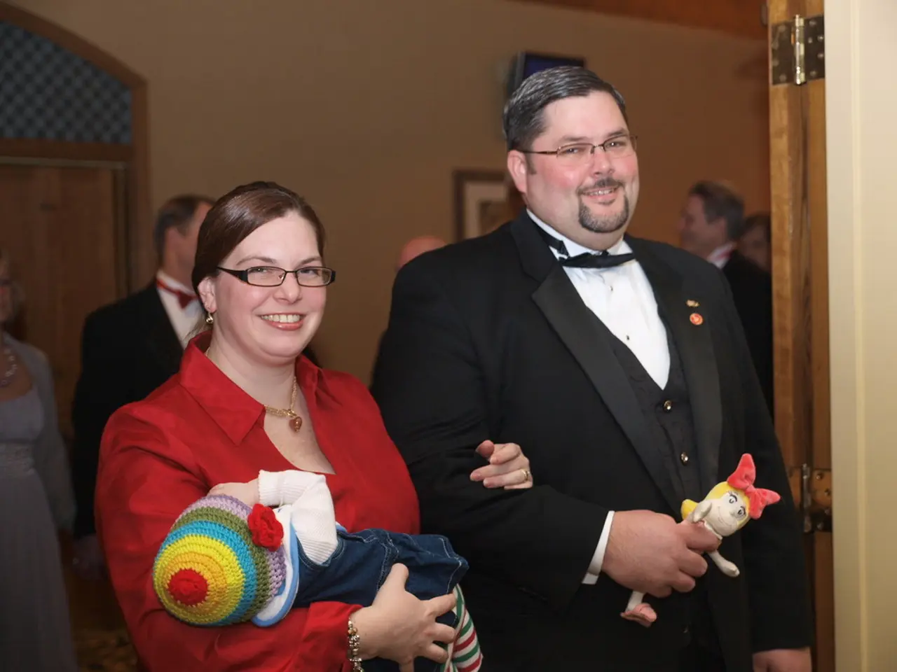 In this image there are many people. In the foreground there is a couple standing with a baby....