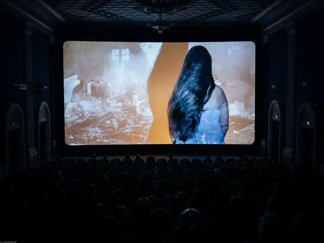 In this picture I can observe screen in the middle of the picture. It is looking like theater. The...