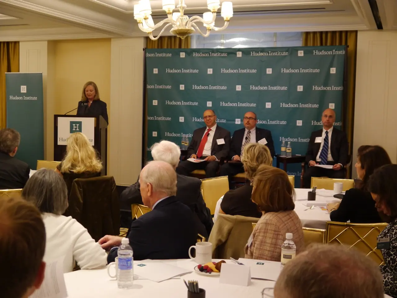 this picture shows a group of people seated on the chair and we see few water bottles, cups and...