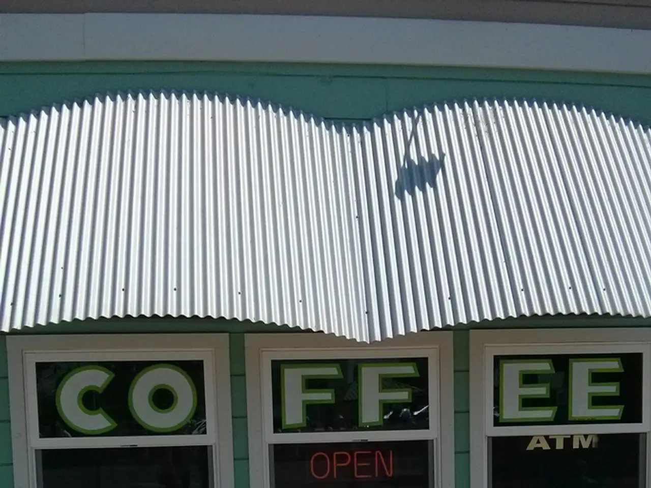 In the center of the image there is a building, wall and a roof sheet. And we can see some text on...