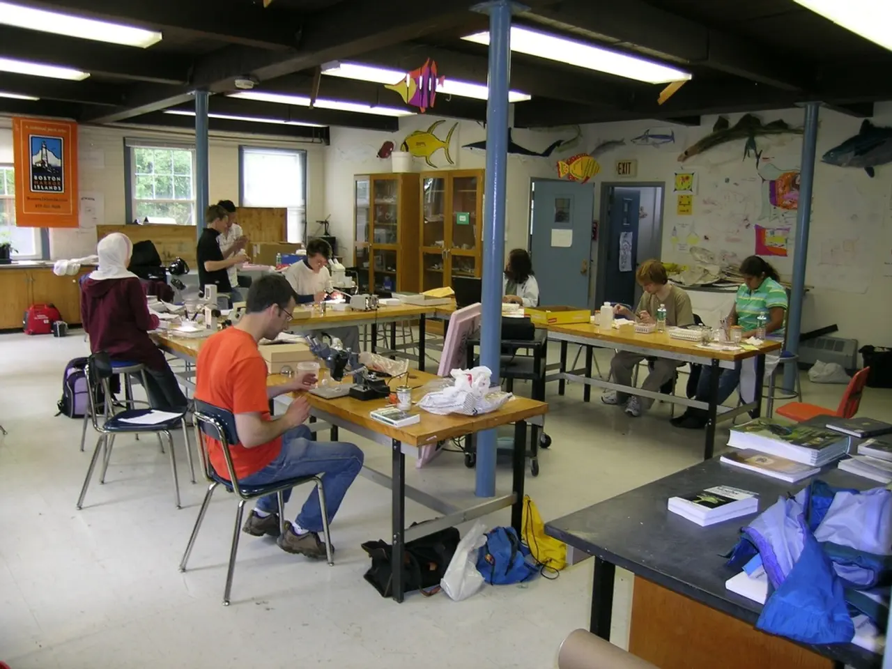 It is a room inside a college there are total four tables there are some papers, books, bottles put...