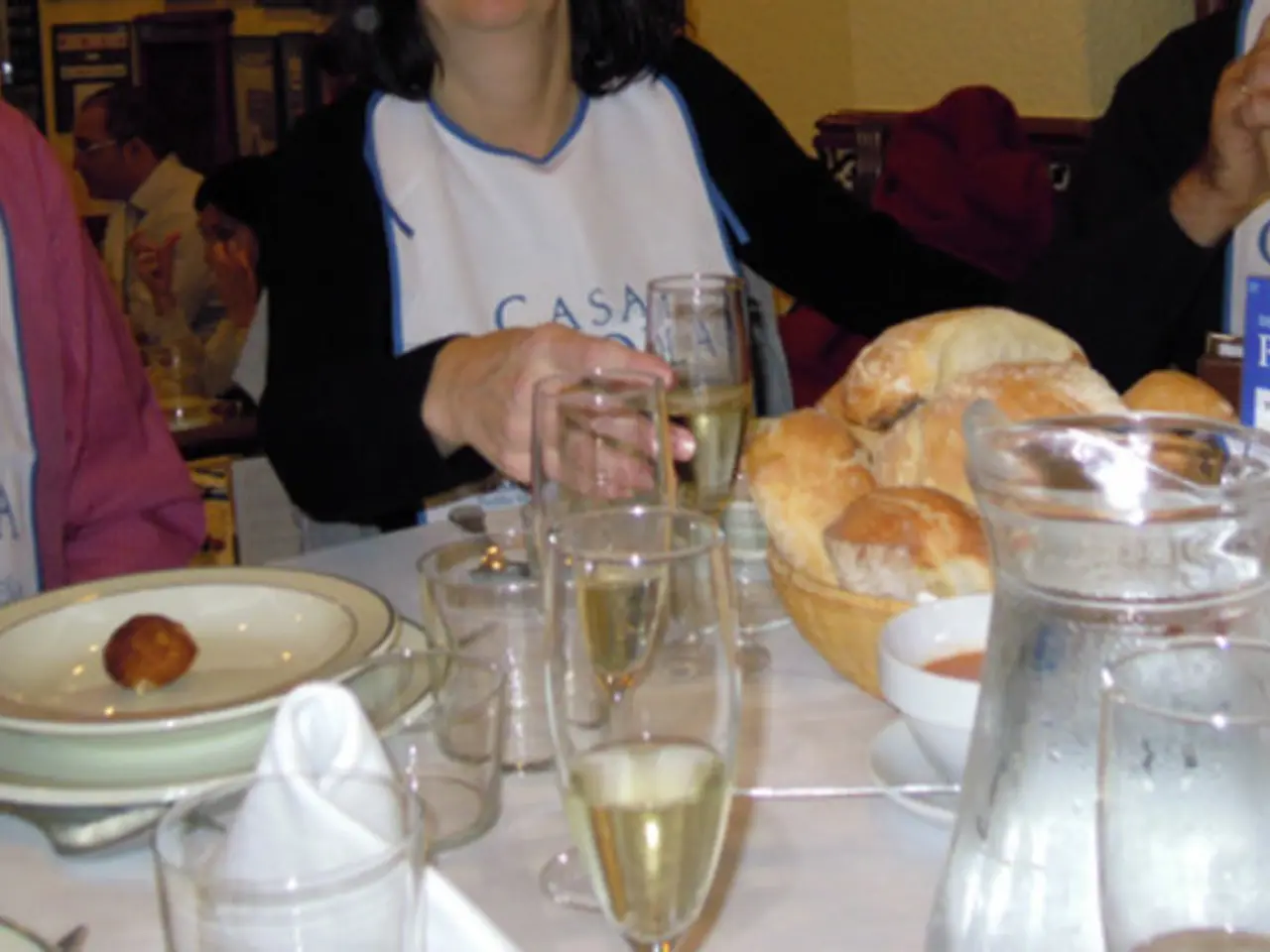 In this image we can see persons sitting on the chairs and tables are placed in front of them. On...