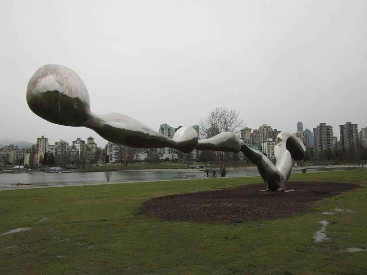 In the foreground of the picture there are soil, grass and a sculpture. In the center of the...