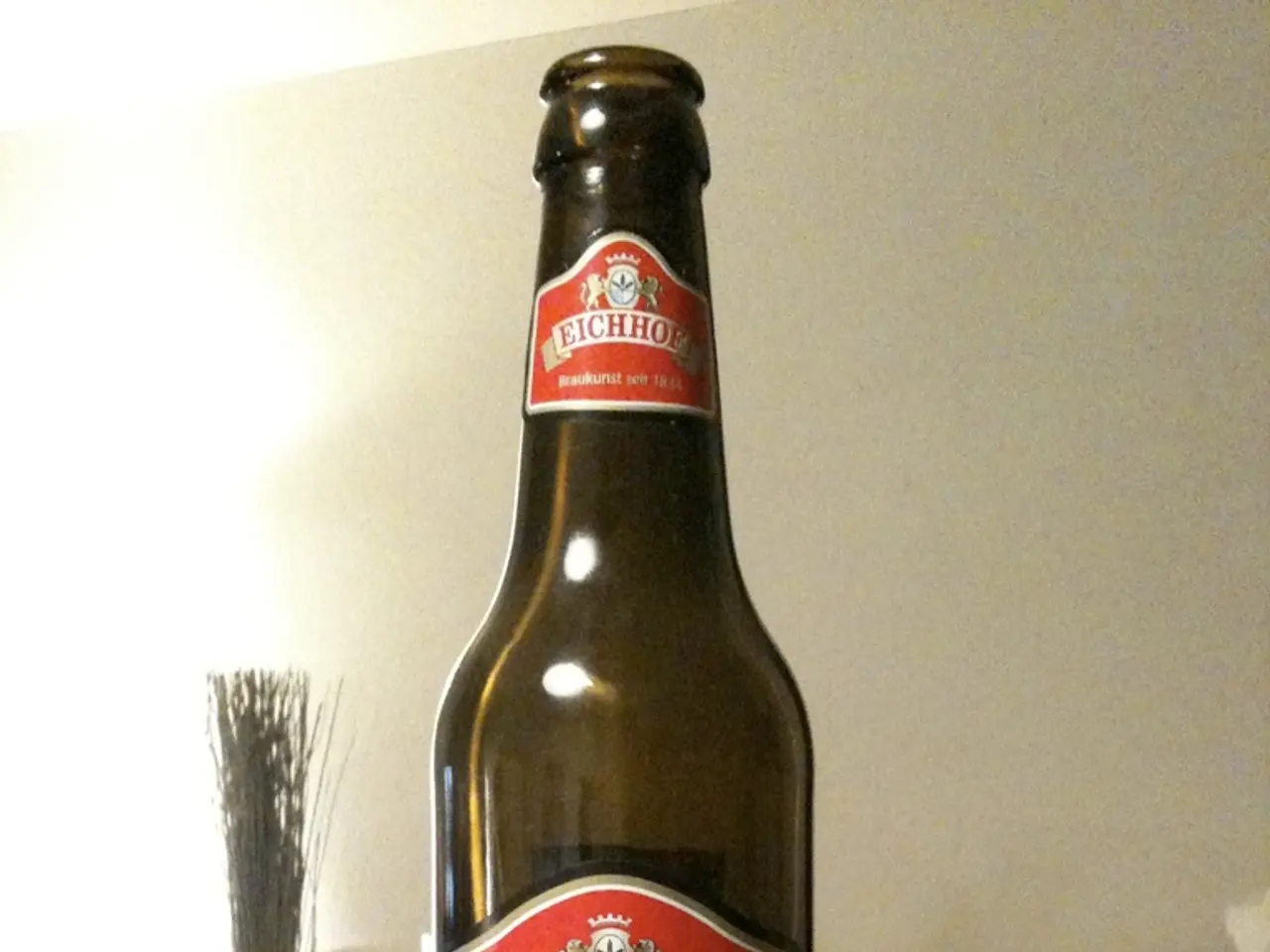 there is a glass bottle on which pony name label is attached. behind the bottle there is a white...