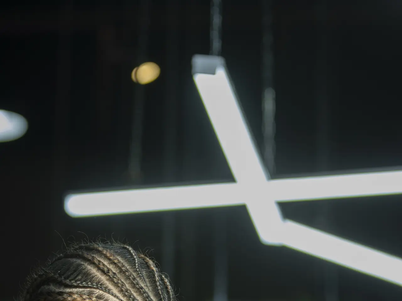 The image shows a man getting his hair cut at a barber shop. He is wearing a black t-shirt and is...