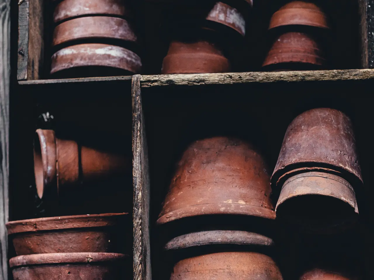 The image shows a wooden box filled with a variety of terracotta pots of different sizes and...