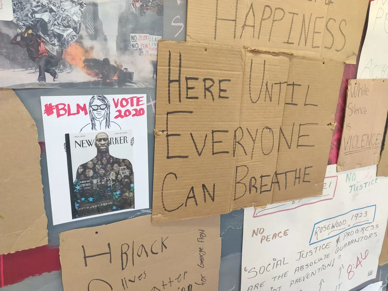 The image shows a wall with a variety of posters and boards attached to it, each with text written...