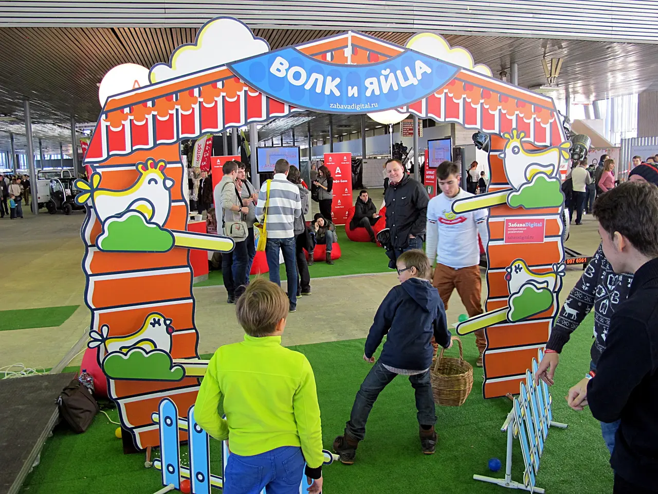 The image shows a group of people standing around a carnival tent, with some of them holding...