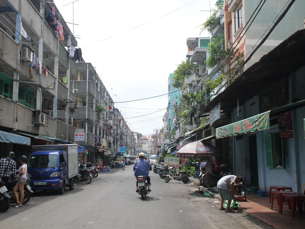 The image shows a bustling street in Hanoi, Vietnam, with people riding motorcycles and cars...