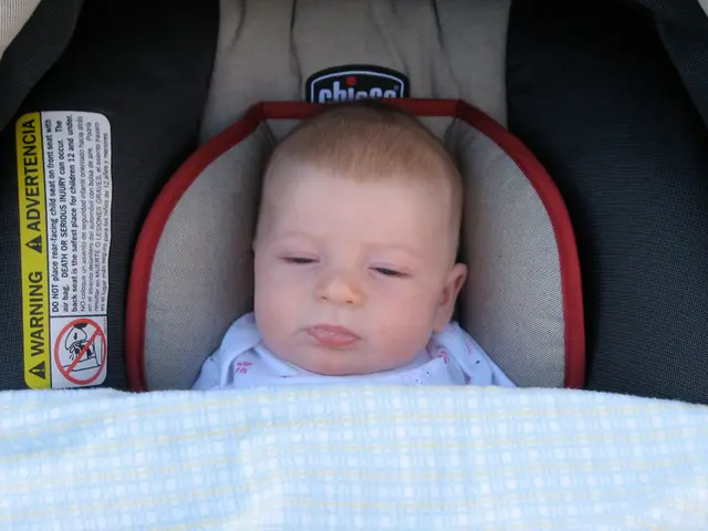 In the image there is a baby laying under baby cradle, on the left side there is a caution sticker...