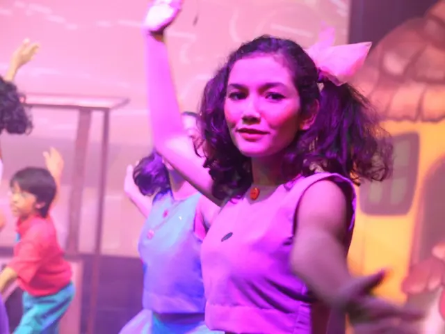 In this image few girls and boy are dancing before a wall having some painting on it.