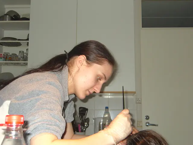 In this image there is a woman sitting and applying a cream on another person 's hair ,and at the...