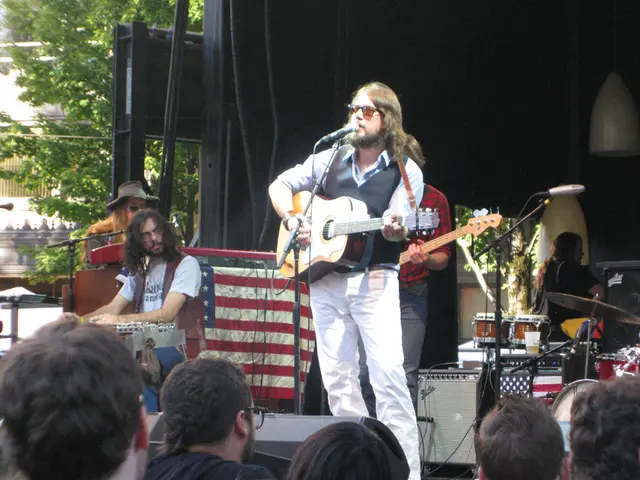 Here in the center we can see a man playing a guitar and singing a song with a microphone in front...