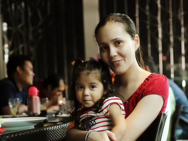 there is a woman sitting holding a baby on the chair beside her there are so many men sitting.