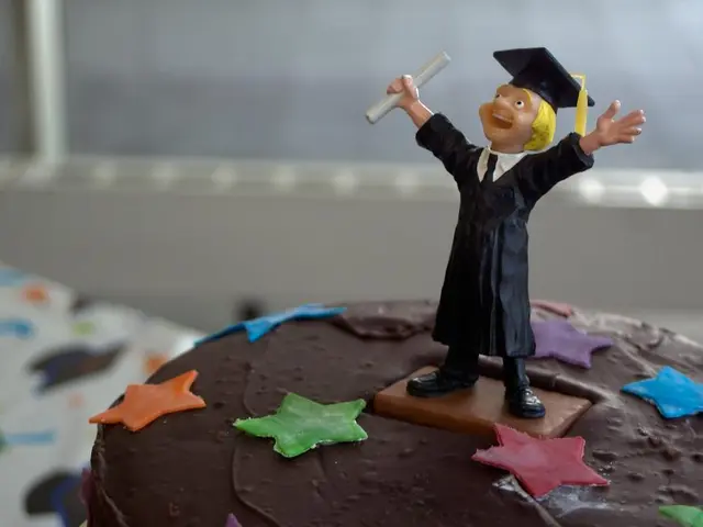 In the picture there is a cake and on the cake there is a doll of a graduate and the background of...