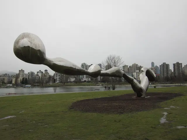 In the foreground of the picture there are soil, grass and a sculpture. In the center of the...