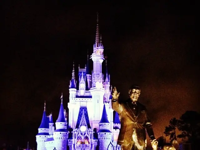 There are statues on the right side of the image and there is a Cinderella castle in the background...