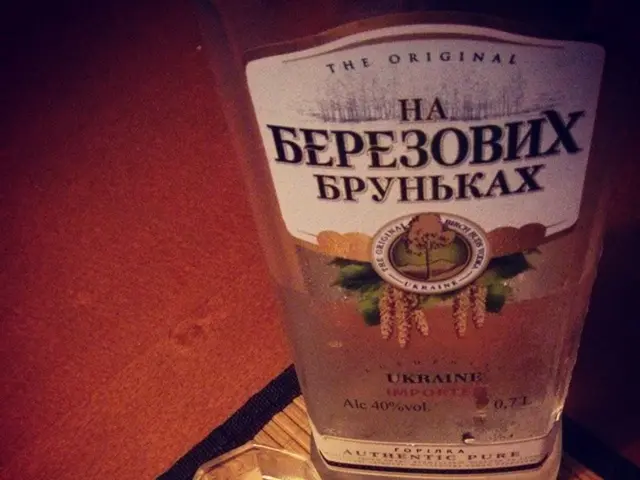 In this image I can see a bottle of alcohol. This is a tumbler placed on the mat.