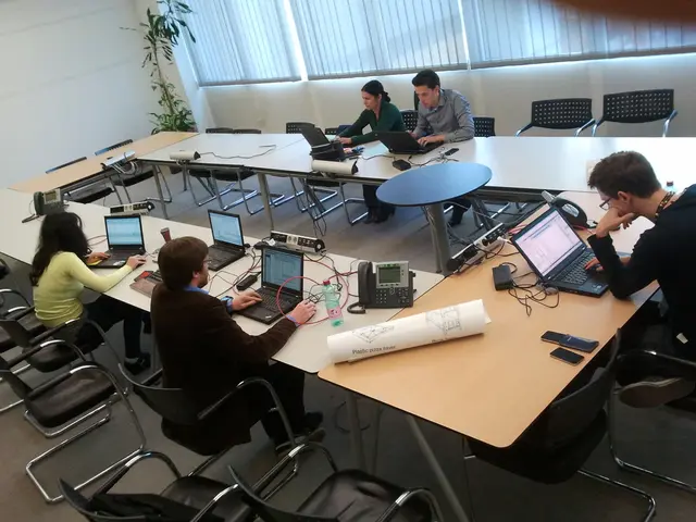 In this image i can see three man sitting on a chair and doing work in a laptop, there are two...