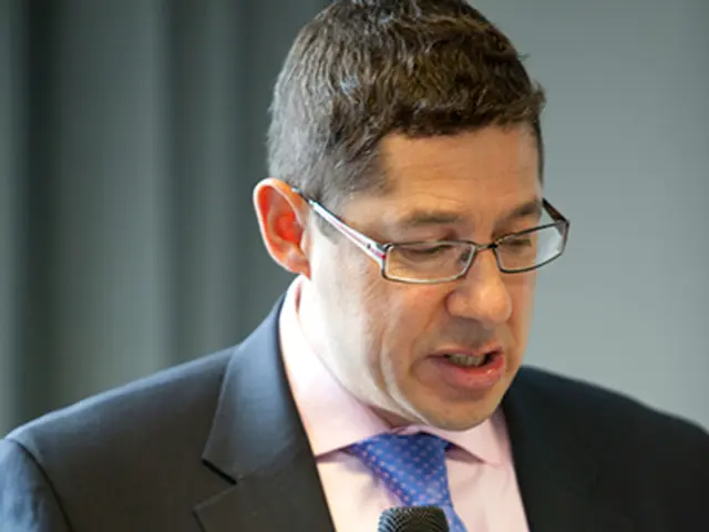 This is the man wearing suit,shirt,tie and spectacles. He is holding mike and talking. This is a...