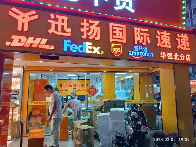 The image shows a DHL and FedEx store in Shanghai, China. There are several people standing in...