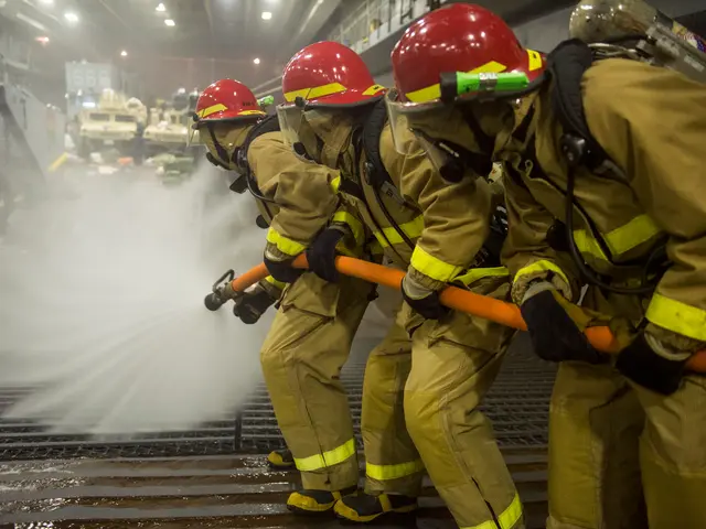 The image shows a group of firefighters wearing helmets and gloves, holding pipes and spraying...