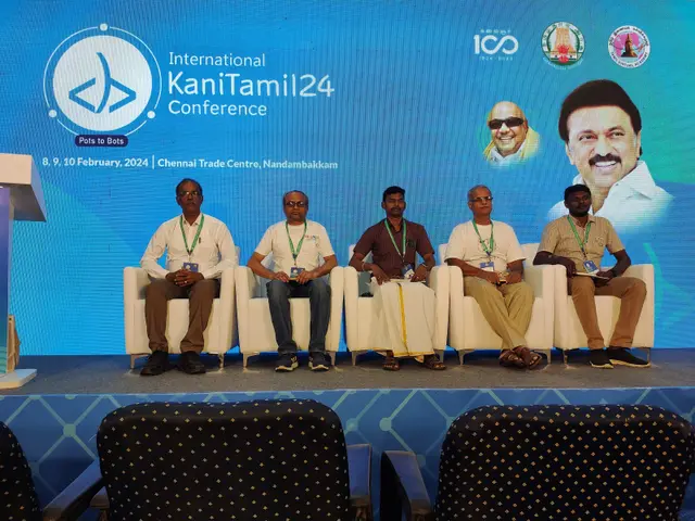 The image shows a group of people sitting on chairs in front of a podium with a microphone, with a...