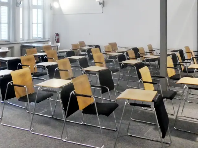 The image shows a classroom with rows of chairs and desks arranged in neat rows, a pillar in the...
