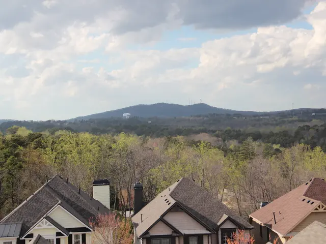 The image shows a view of a residential neighborhood from the top of a hill, with a number of...