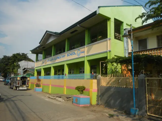 The image shows a school building with a green and yellow facade on the side of a street,...