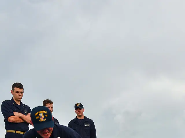The image shows a group of men in navy uniforms doing push ups on a blue mat on the deck of a ship....