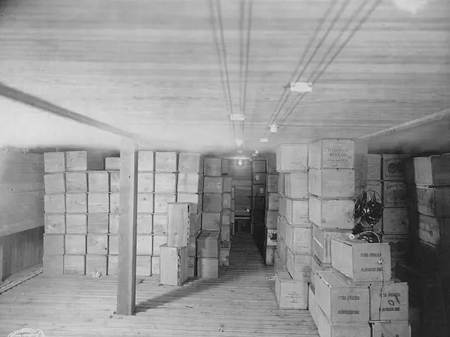 The image shows a black and white photo of a room filled with lots of cardboard boxes on the floor...
