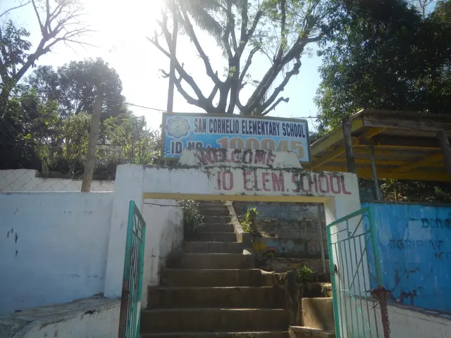 The image shows the entrance to a school with stairs leading up to it, a gate, a wall, a fence, a...