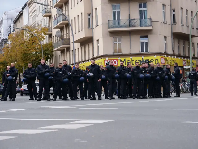 The image shows a group of police officers standing in the middle of a street, wearing black...