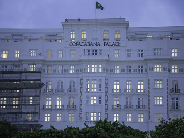 The image shows the Copacabana Palace Hotel in Rio de Janeiro, Brazil. It is a large white building...