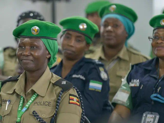 The image shows a group of women in police uniforms sitting next to each other, wearing green caps...