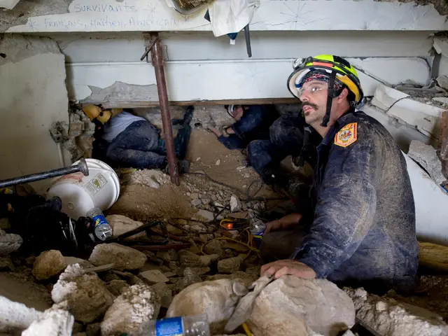 The image shows a firefighter wearing a helmet and sitting in the rubble of a collapsed building,...
