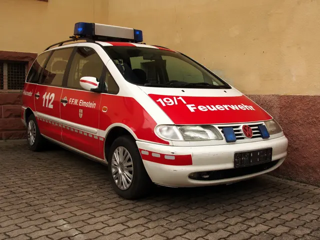 The image shows a red and white minivan parked in front of a building with windows. The minivan has...