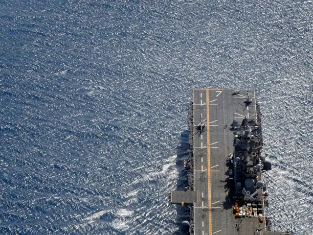 The image shows an aircraft carrier, the USS George H W Bush CVN-68, transiting the Arabian Sea. On...