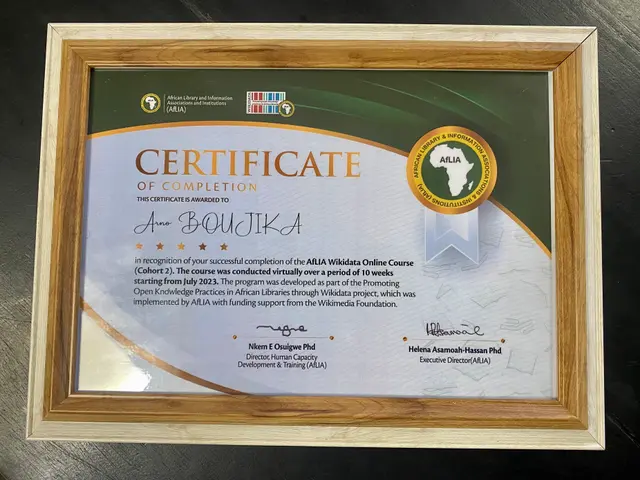 The image shows a certificate of completion placed on a table. The certificate is framed and has...