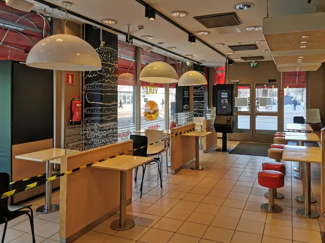 The image shows the interior of a fast food restaurant with tables and chairs, stools, a floor, a...