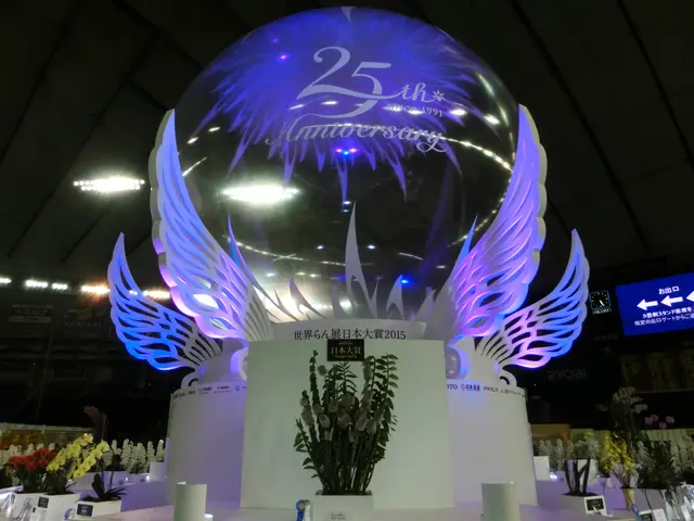 The image shows a large crystal ball with wings on top of it, surrounded by flower bouquets, name...