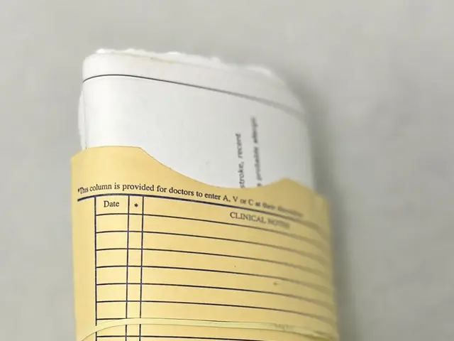 The image shows a roll of paper with a yellow ribbon tied around it, sitting on top of a table. The...