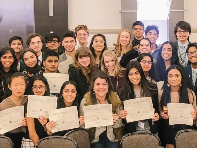 The image shows a group of people posing for a photo with certificates in their hands, surrounded...