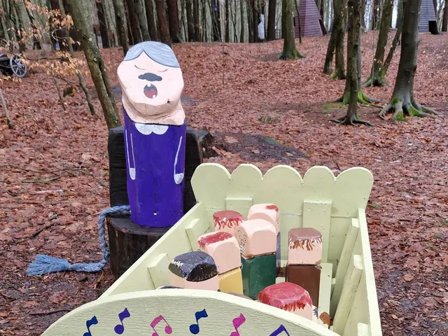 The image shows a wooden box filled with lots of different colored toys sitting on top of a forest...