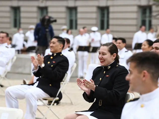 The image shows a group of people in military uniforms clapping and clapping in front of a building...
