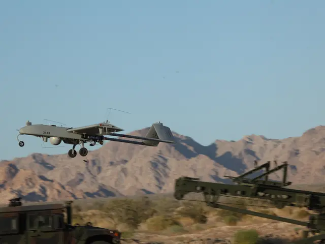 The image shows an MQ-9 Reaper Unmanned Aerial Vehicle (UAV) flying over a military vehicle in the...