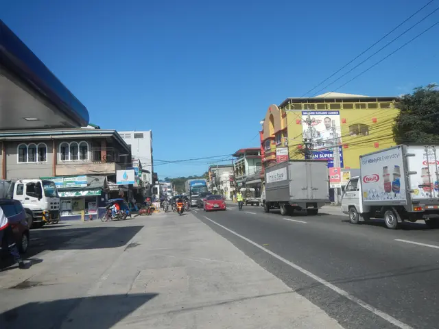 The image shows a city street filled with lots of cars and trucks, as well as people walking on the...