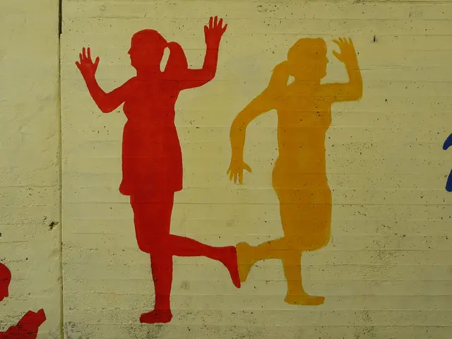 The image shows a mural on the side of a building depicting two people playing soccer. The painting...